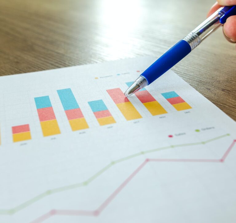 person holding pen pointing at graph